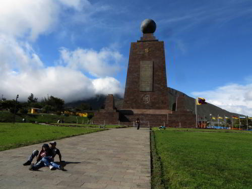 WHAT IS MITAD DEL MUNDO MONUMENT? Visitors posing in front of the monument. 